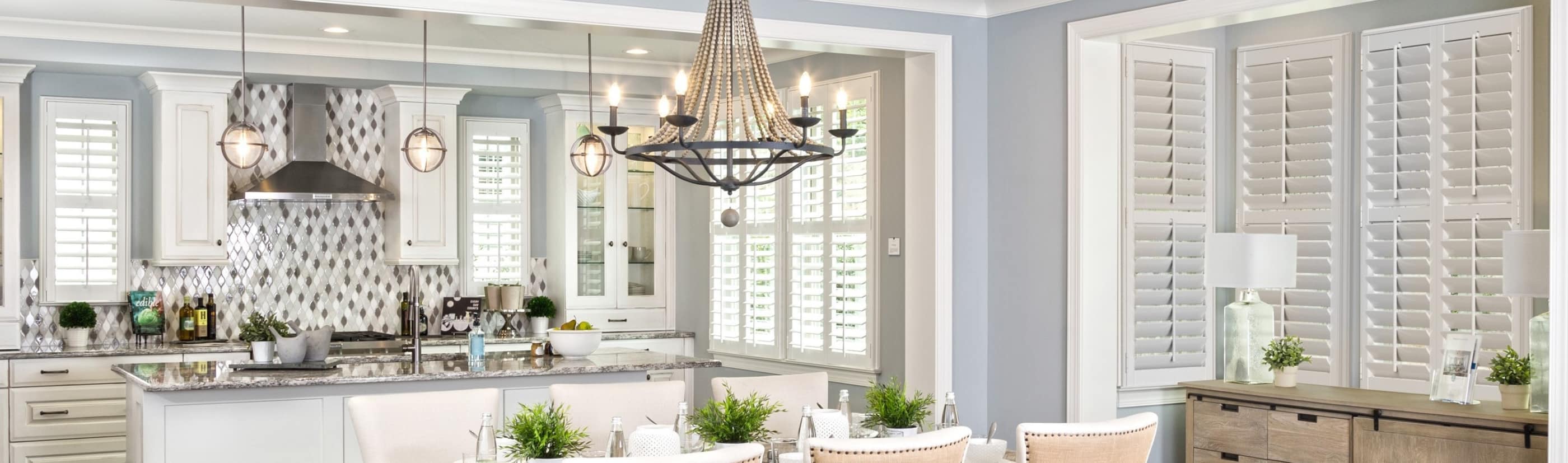 White Polywood shutters on large windows in a farmhouse-style living and dining room.